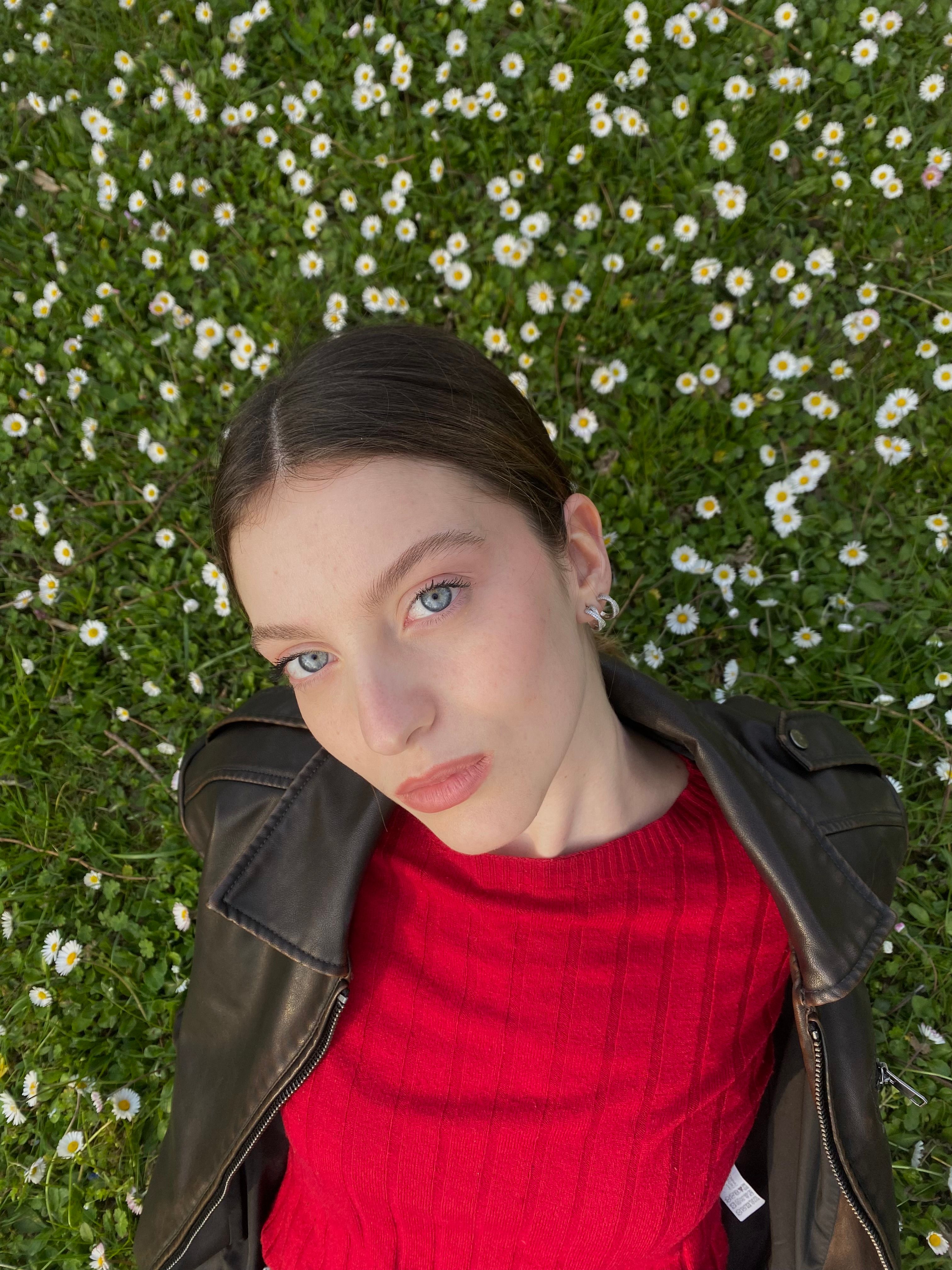 Woman in leather jacket lying on a daisy-filled meadow, Sesto San Giovanni.