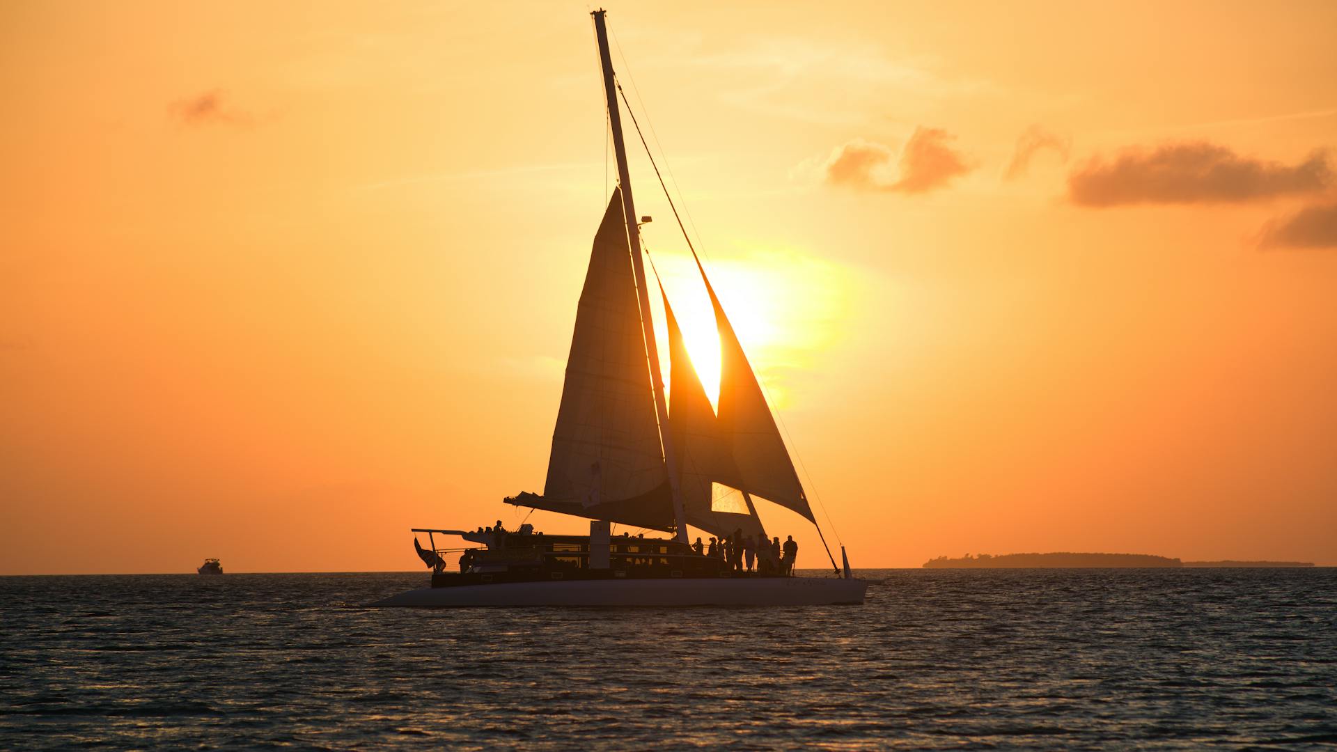 A sailboat silhouetted against a vibrant Key West sunset, showcasing a serene tropical paradise.