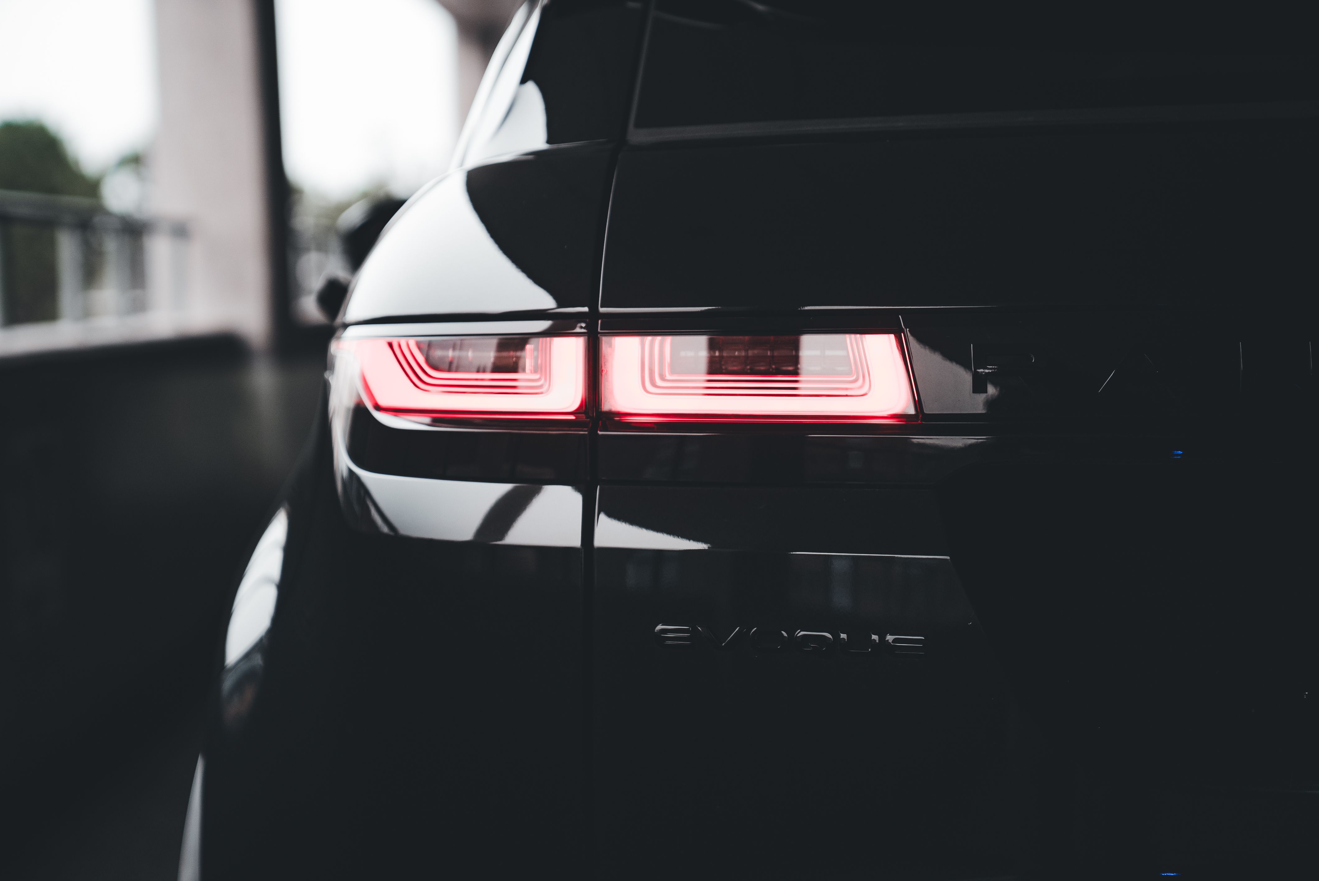 Close-up of a black SUV's sleek tail light in a dark environment.