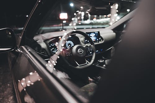 A car interior at night with the steering wheel and dashboard