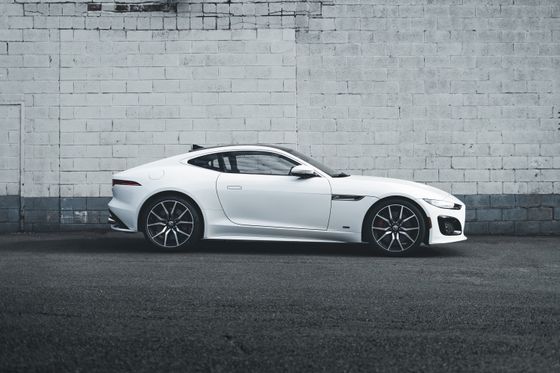 White sports coupe in side profile against a grey painted brick wall. Photo by Erik Mclean on Pexels