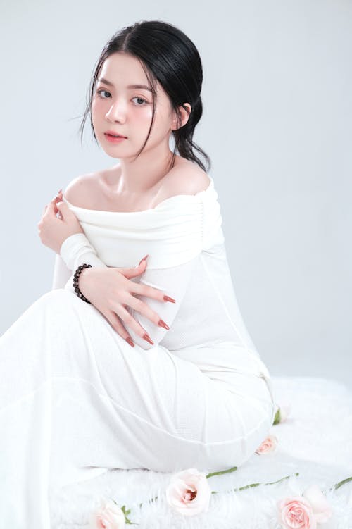 A woman in white dress sitting on white rug