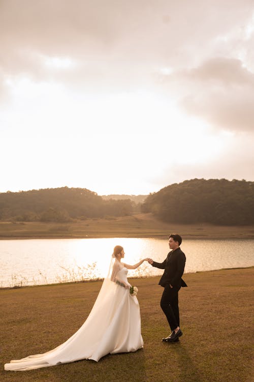 Newlyweds Standing by River at Sunset