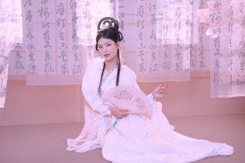Free A woman dressed in traditional Asian attire poses elegantly indoors holding a decorative fan. Stock Photo