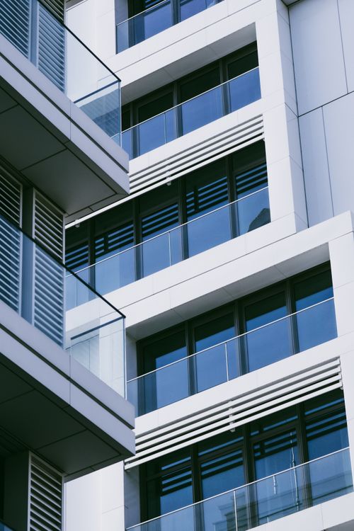 Free Contemporary urban apartment building facade with glass balconies and geometric design. Stock Photo