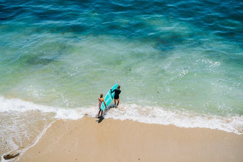 Two people walking on the beach with surfboards