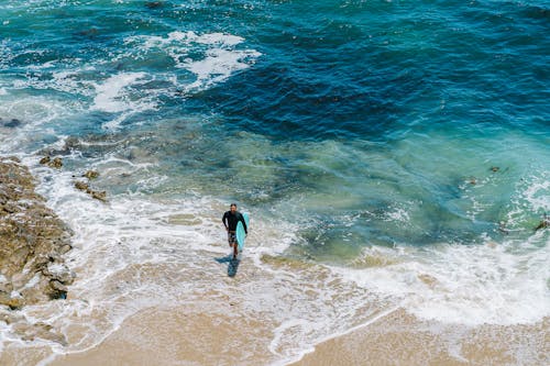 A surfer walks out of the water and into the ocean