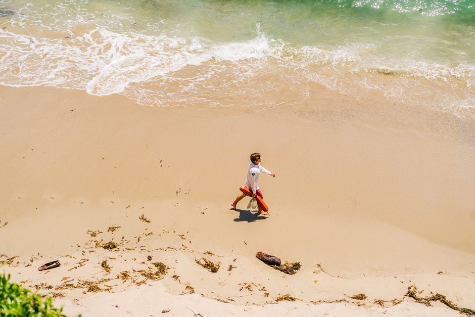 Aerial view of a lifeguard walking on a sandy beach by the ocean.