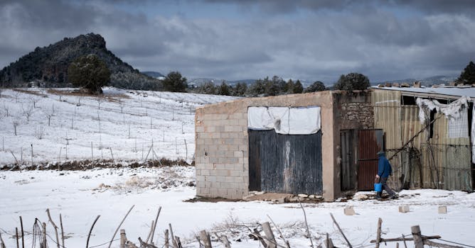 Abandoned building in winter landscape at Sierra Nevada with a person walking by.