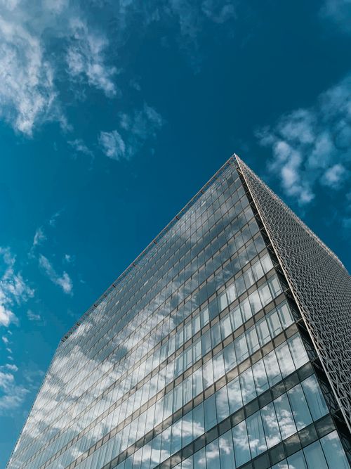 Free A stunning view of a glass skyscraper reflecting the clouds and the blue sky, showcasing modern architecture. Stock Photo