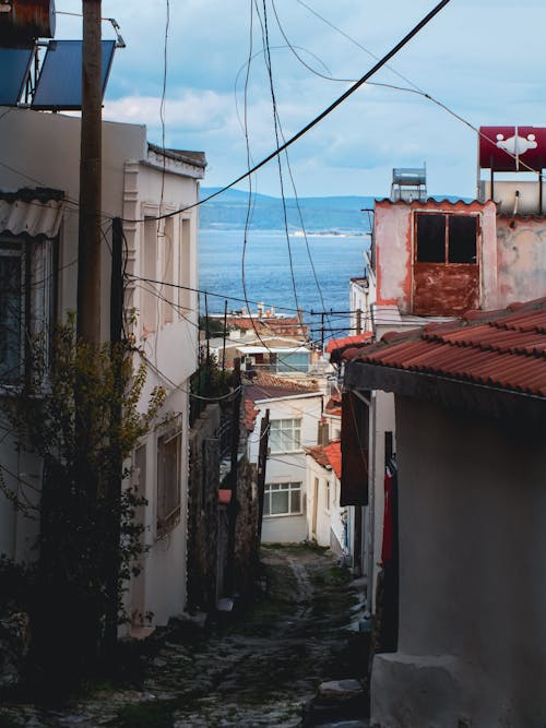 A narrow street with houses and a view of the sea