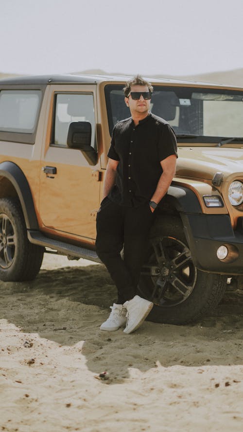 A man standing next to a jeep in the desert
