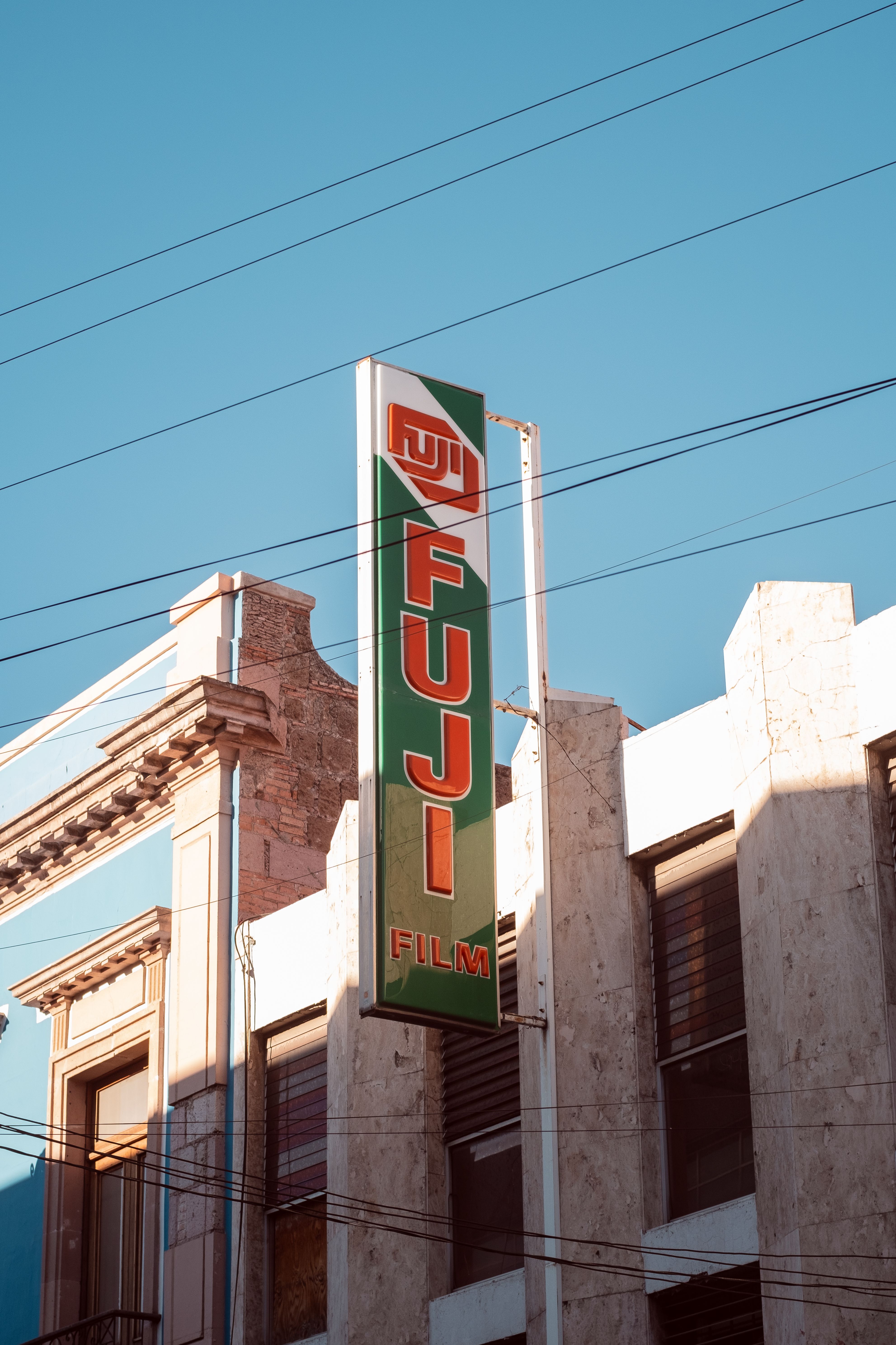 Fujifilm sign on urban building facade in Aguascalientes, Mexico under clear blue sky.