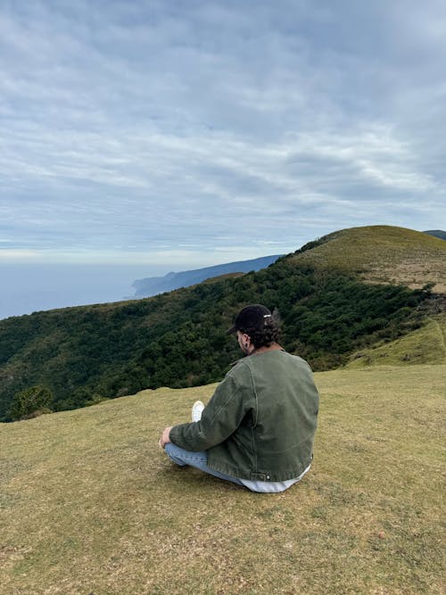 A person sitting on a hill with the ocean in the background