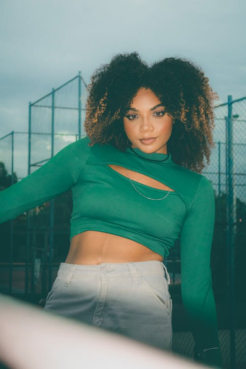 A woman with curly hair posing in a green top