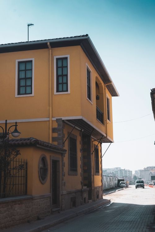 Free Quaint yellow house on a city corner in Konya, Türkiye, under clear blue skies. Stock Photo