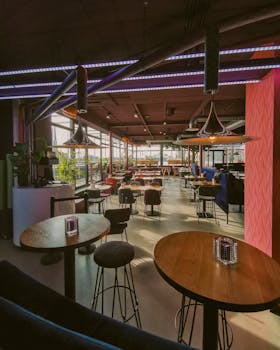 A well-lit modern café interior featuring stylish furniture and hanging lamps.