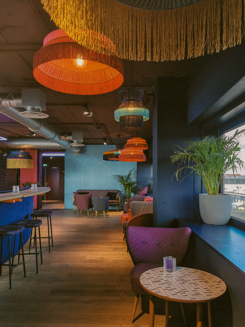 Free Stylish interior of a modern restaurant featuring vibrant lighting and cozy seating. Stock Photo