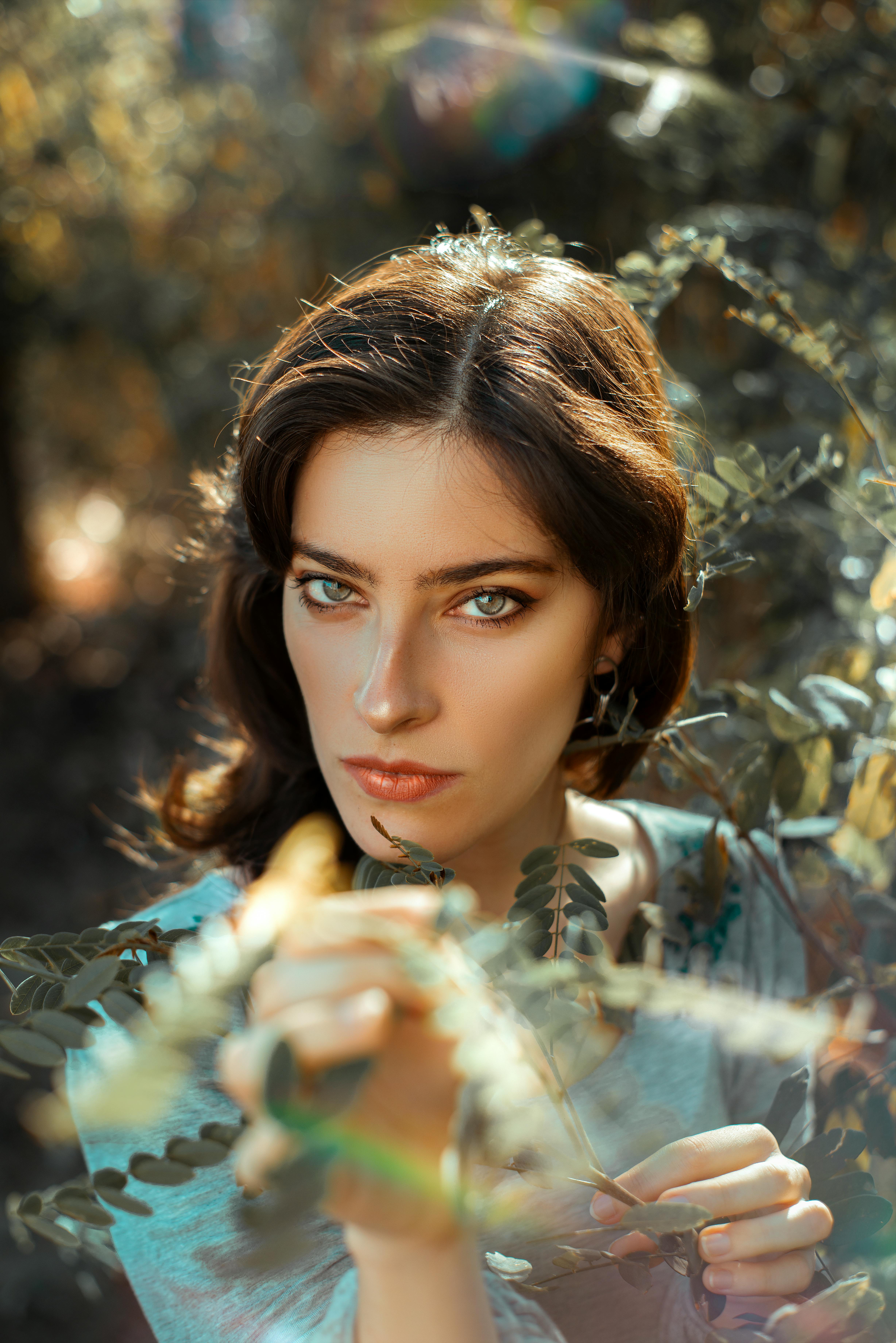Captivating portrait of a woman surrounded by vibrant leaves in an outdoor setting.