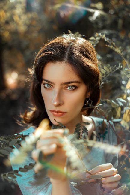 Captivating portrait of a woman surrounded by vibrant leaves in an outdoor setting.