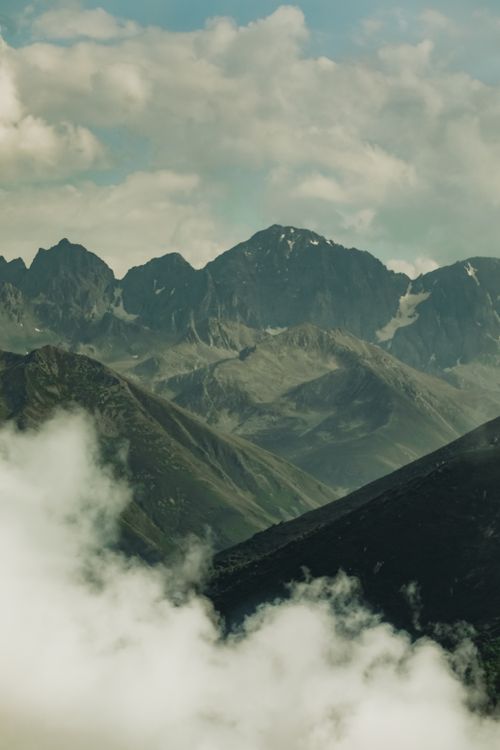 Free Stunning aerial view of rocky mountain range with clouds and clear sky. Stock Photo