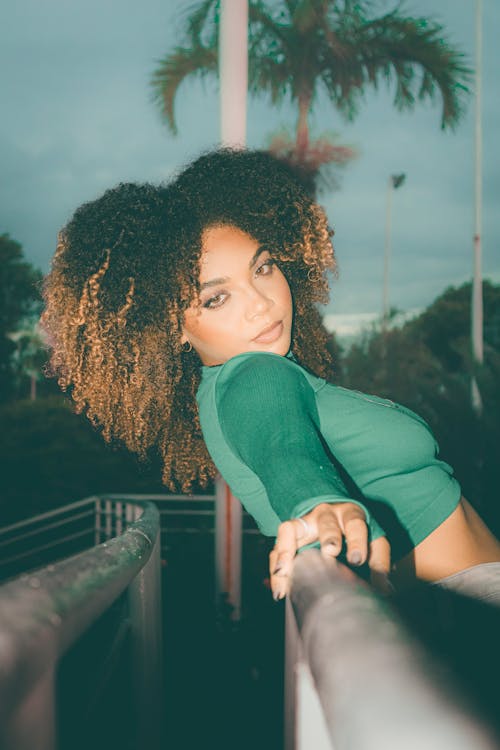 A woman with curly hair posing on a railing