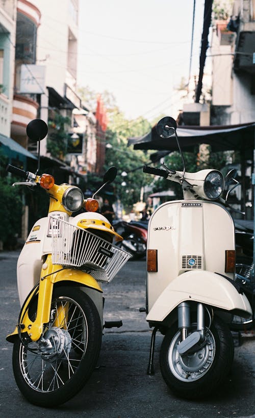 Two yellow and white scooters parked on the street