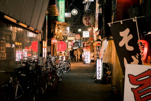 Bicycles Parked Near Japanese Store during Night Time