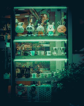Explore a charming store display featuring glowing animal figurines and a variety of ceramics under green light. Perfect for night scenes.