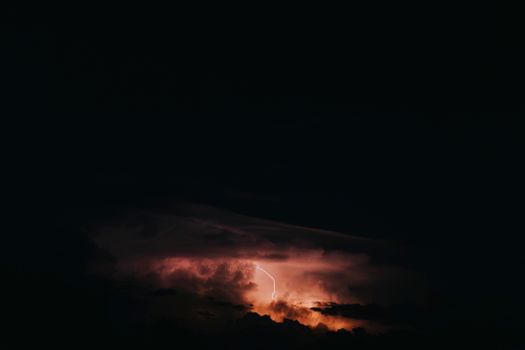 A powerful lightning strike illuminates the nighttime sky during a dramatic thunderstorm.