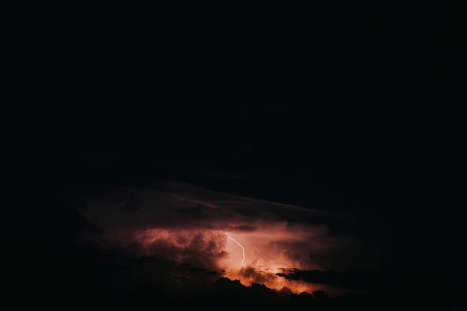 A powerful lightning strike illuminates the nighttime sky during a dramatic thunderstorm.