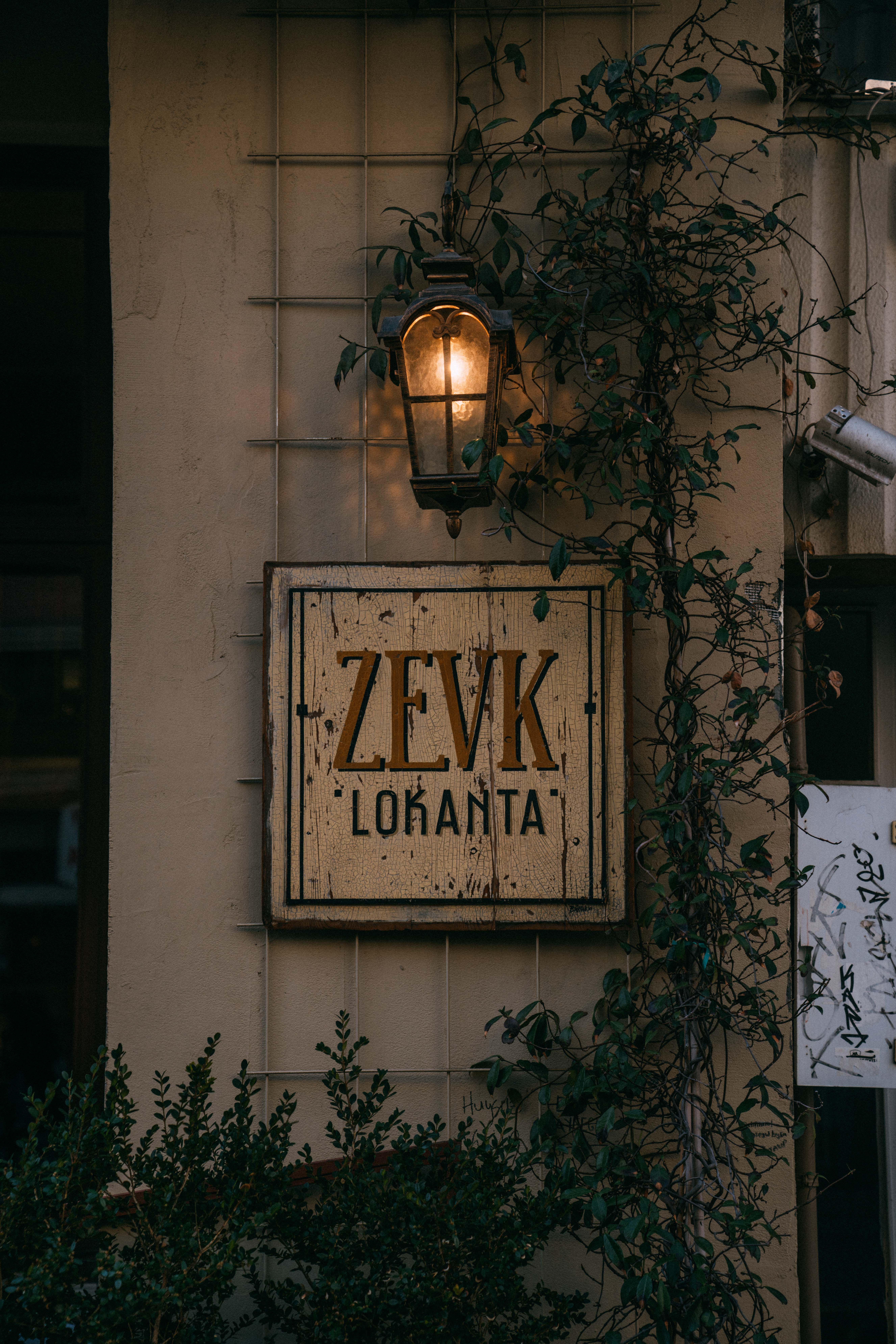 A quaint urban restaurant facade with vintage sign and ivy climbing the wall.