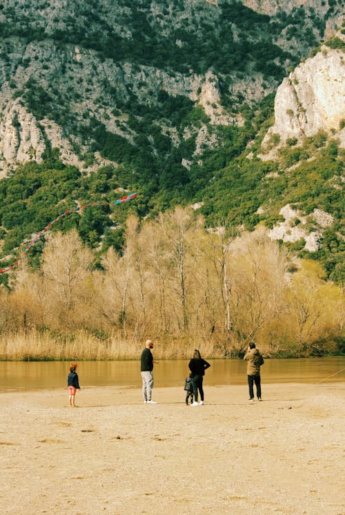 A group of people standing on a beach near a mountain