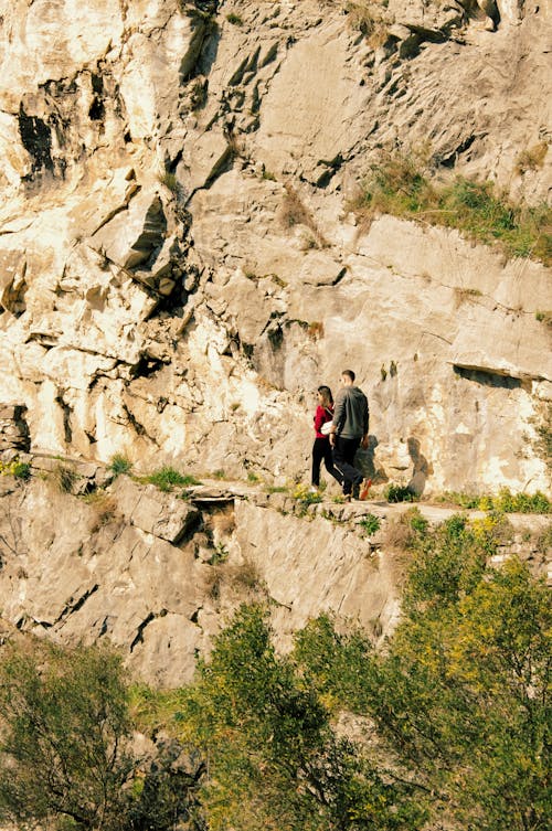 Two people walking on a path near a cliff