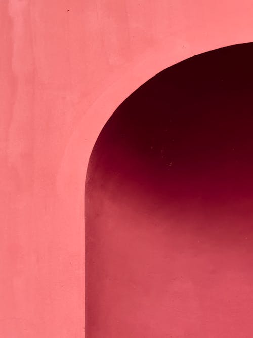 A pink wall with a red archway
