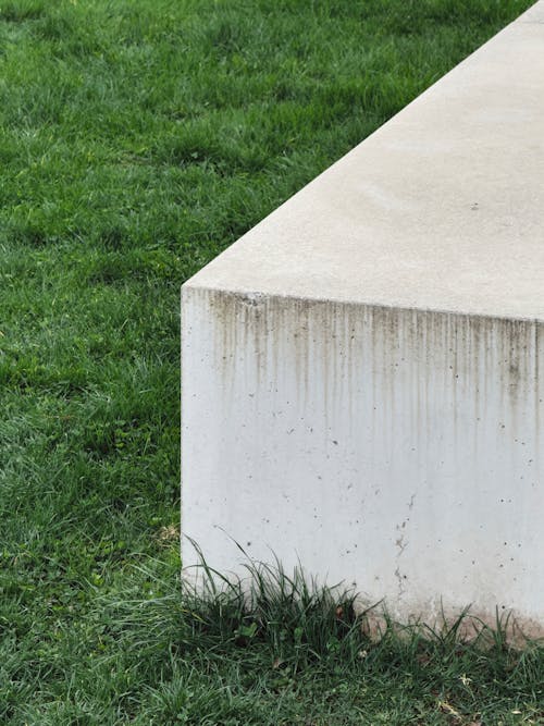 A concrete bench sitting in the grass next to a tree