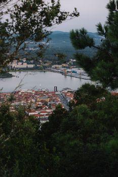 Scenic aerial view of a town by a river framed by lush green trees on a clear day.