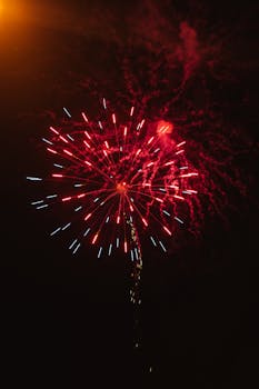 Colorful fireworks display with red and blue sparks in the night sky.