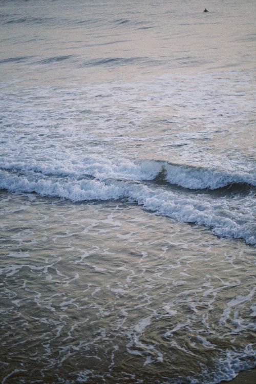 Free Calm ocean waves rolling onto the beach during sunset, creating a serene atmosphere. Stock Photo