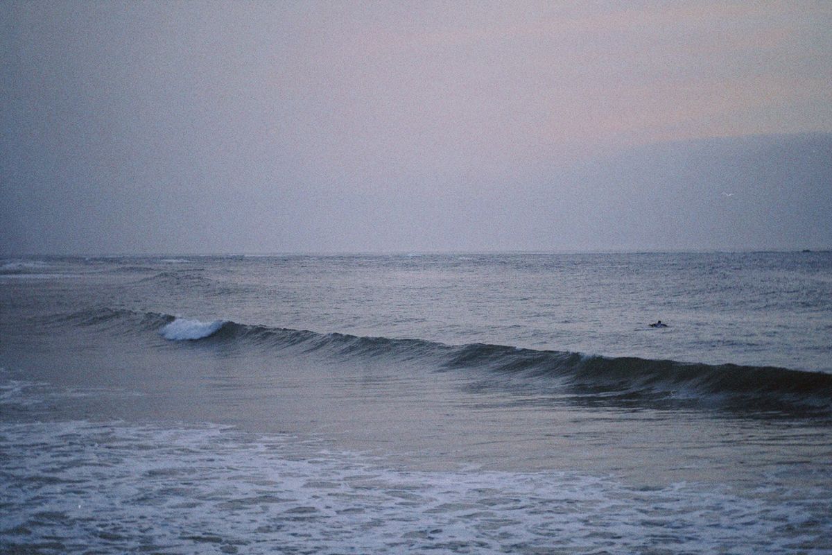 Lone surfer in the ocean at dawn taking advantage of an empty peak during shoulder season