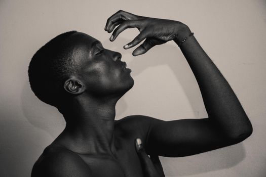 Expressive portrait of a shirtless man creating an artistic pose in sepia.
