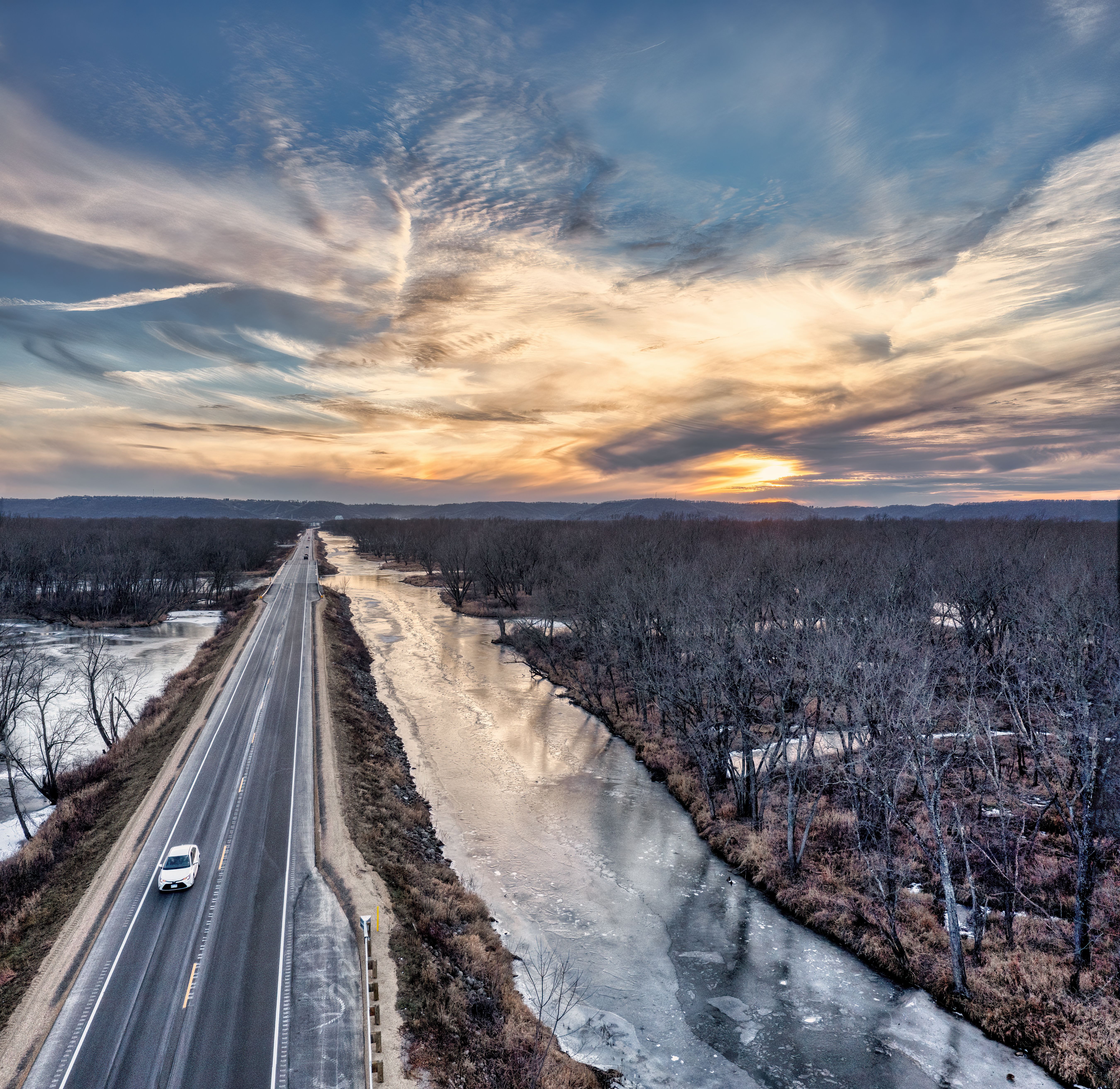 Aerial view of a road and frozen river during winter at sunset in Nelson, WI.