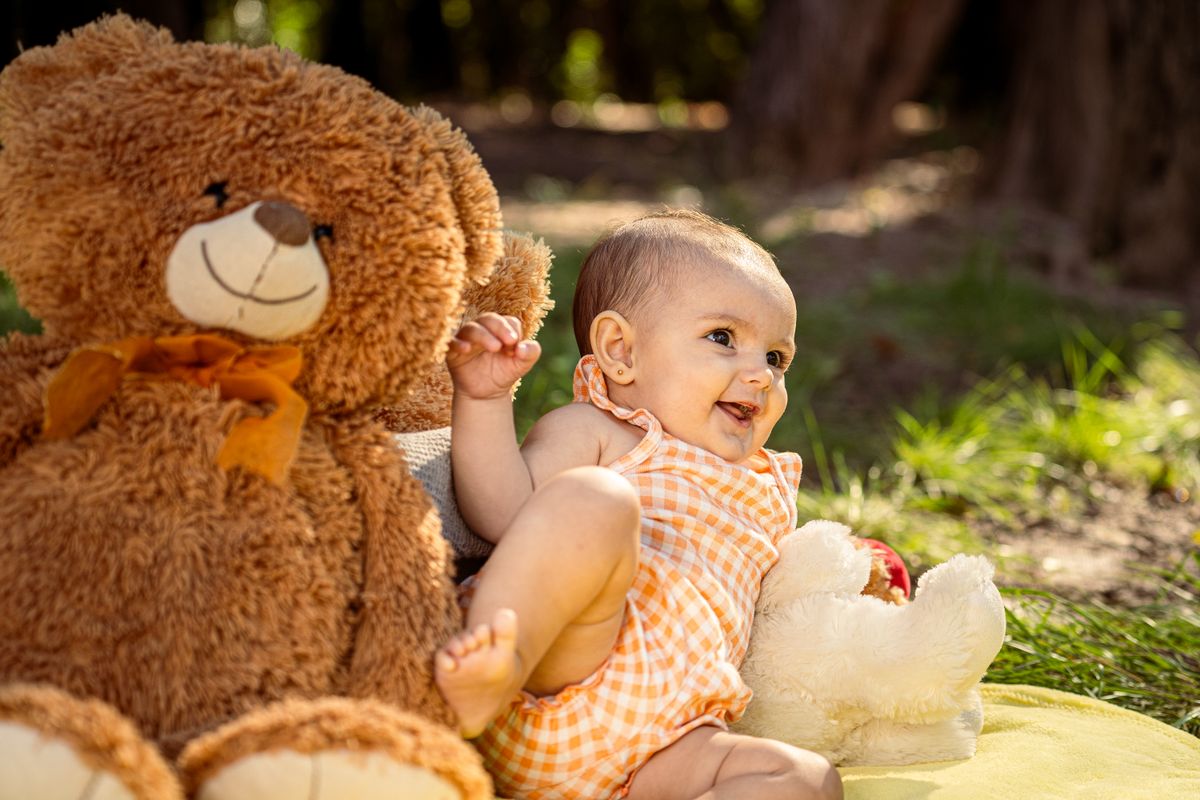 Smiling baby sitting beside a big teddy bear