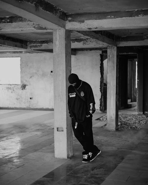 A man in a black hoodie standing in an abandoned building