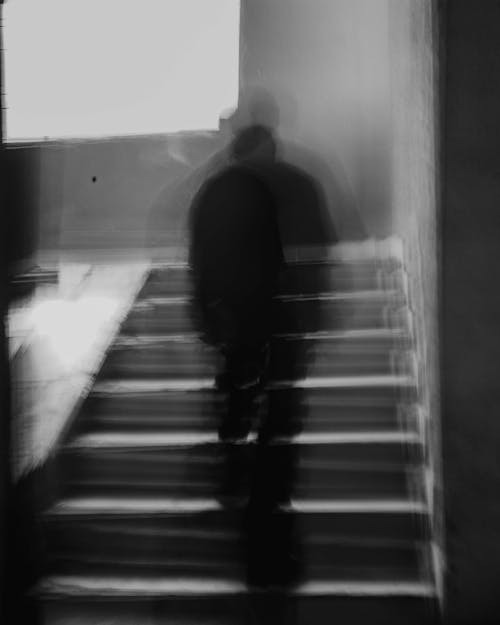 A black and white photo of a person walking up some stairs