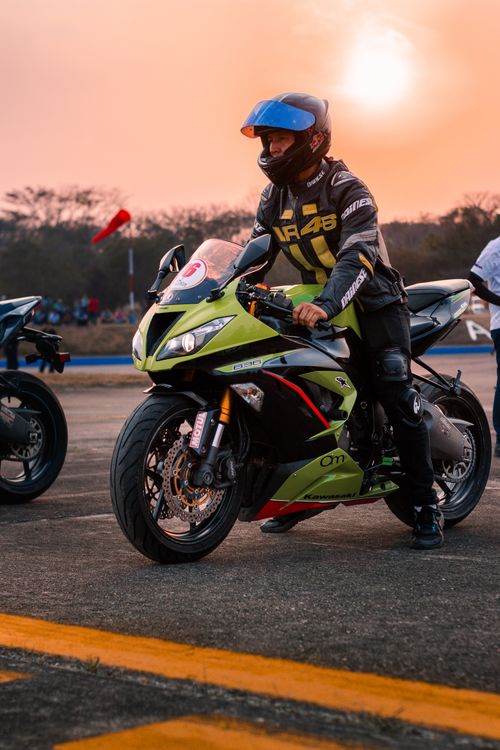 Free A motorcyclist prepares for a race at sunset, highlighting speed and adventure. Stock Photo