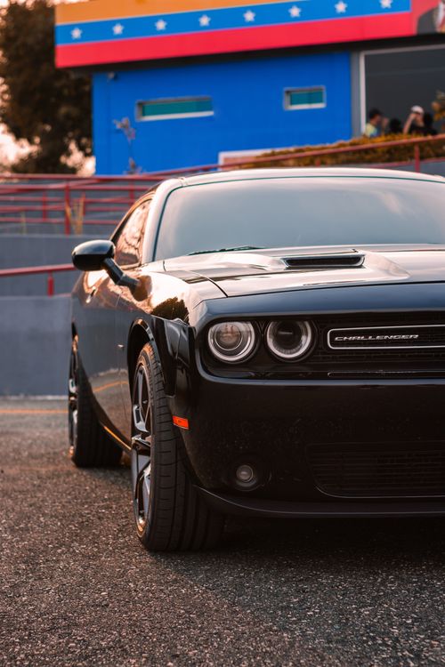 Free Stylish black Dodge Challenger parked in a vibrant urban environment. Stock Photo