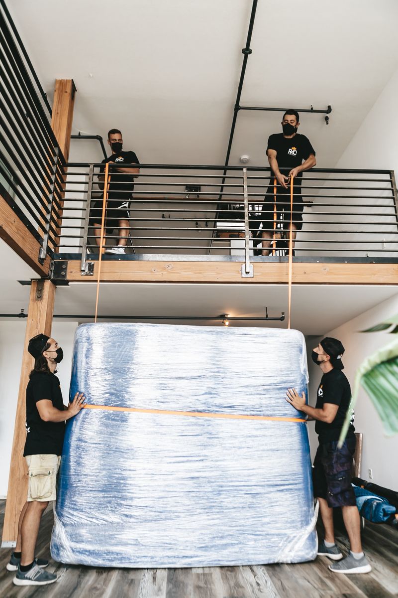 Movers carefully lifting a large wrapped item with straps
