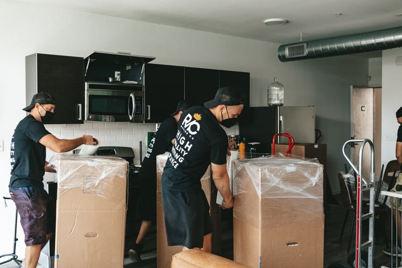 Movers unpacking boxes in an office kitchen setting