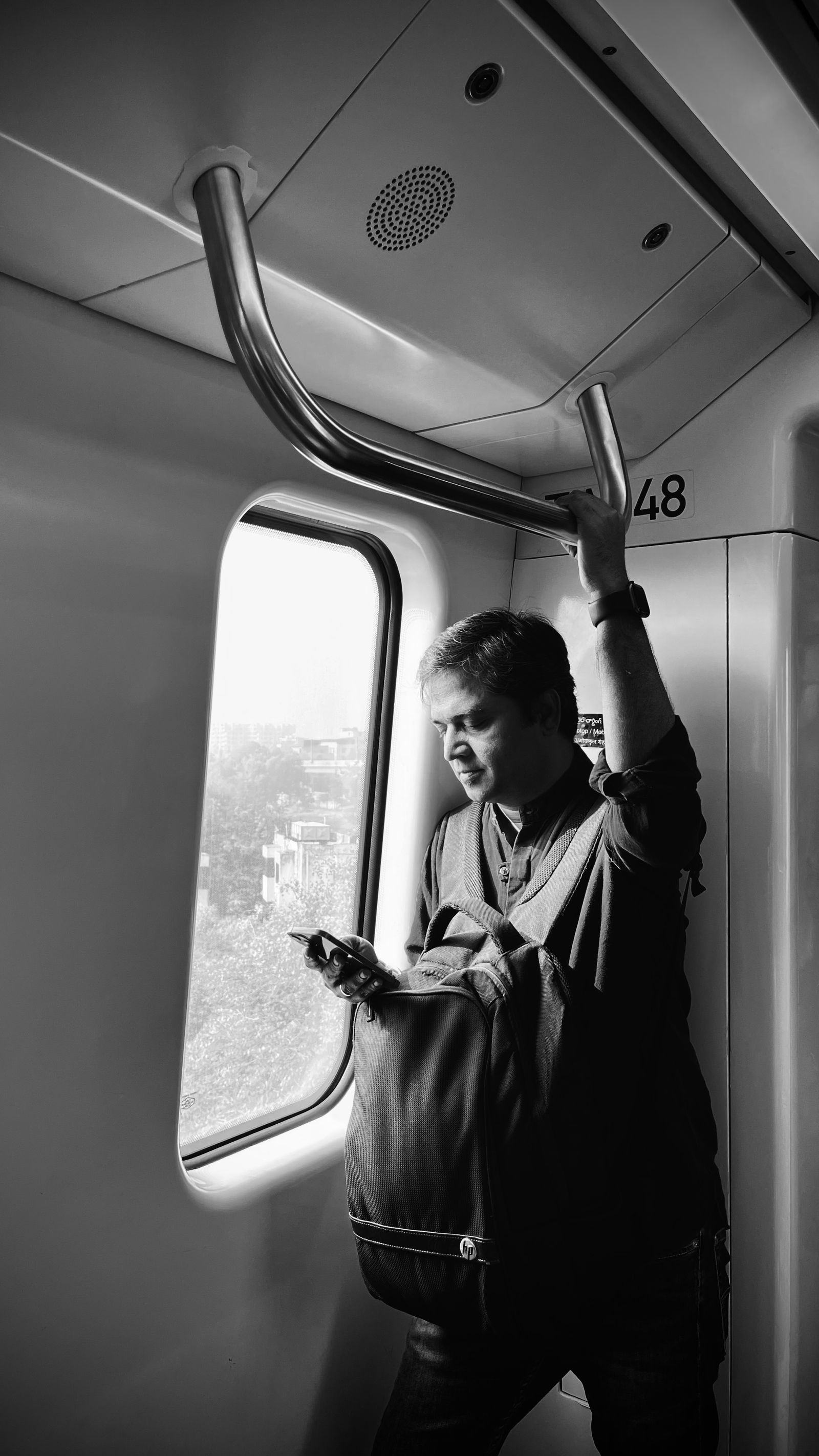 A passenger looking at a smartphone on a train